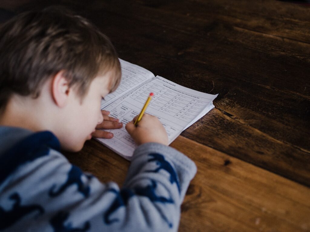 A child doing 11+ summer preparation, writing practice questions at a desk at home